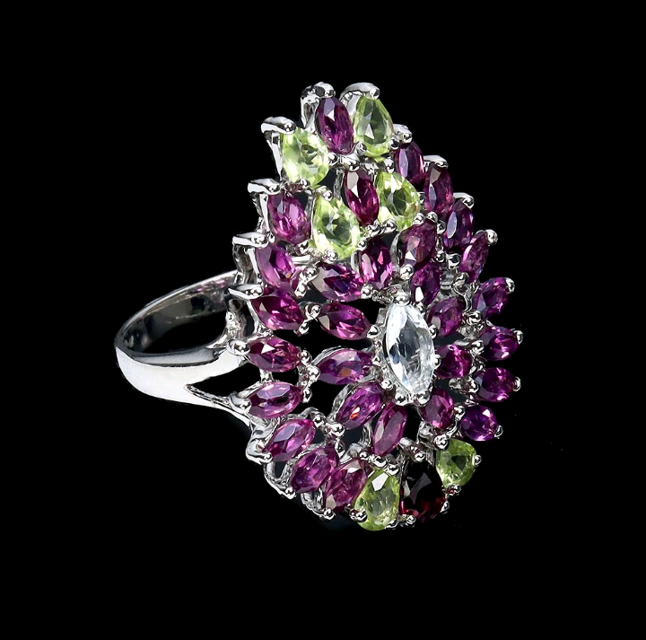 Ring with purple and green gemstones on a black background
