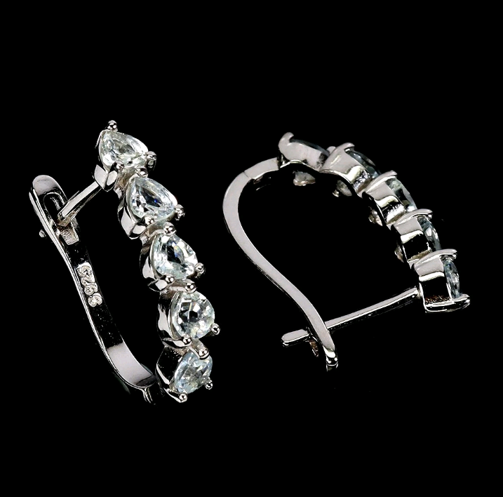 Silver hoop earrings with pear-shaped gemstones on a black background
