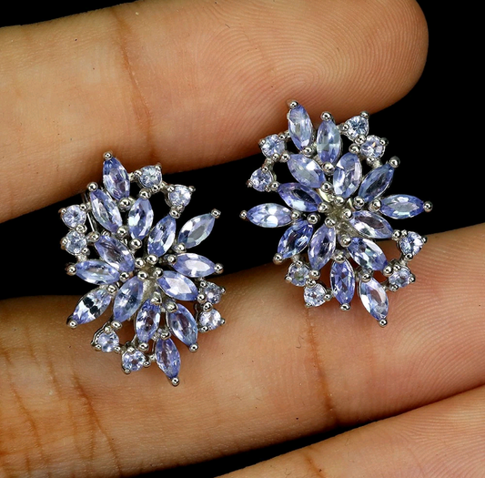 Pair of purple gemstone earrings held between fingers