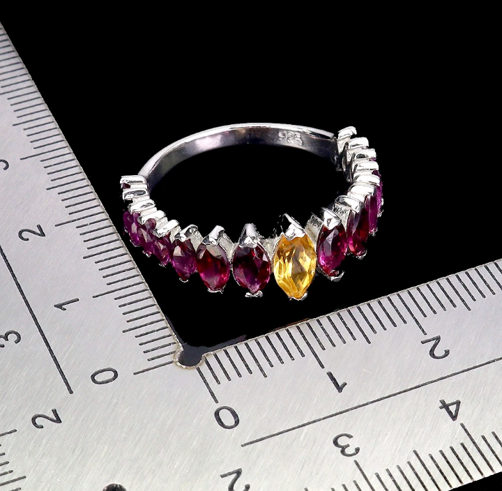 Silver ring with marquise-shaped gemstones on a ruler for size reference