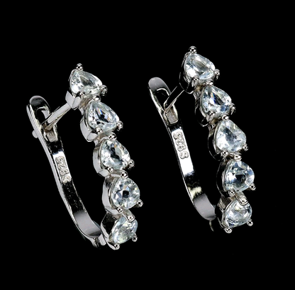 Pair of silver hoop earrings with clear gemstones on a black background