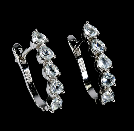 Pair of silver hoop earrings with clear gemstones on a black background