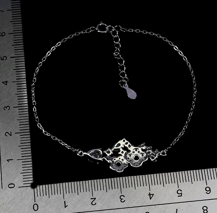 Silver bracelet on a black background with a ruler for scale