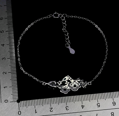 Silver bracelet on a black background with a ruler for scale