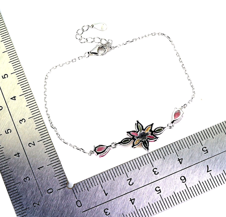 Silver bracelet with floral design on a ruler for size reference