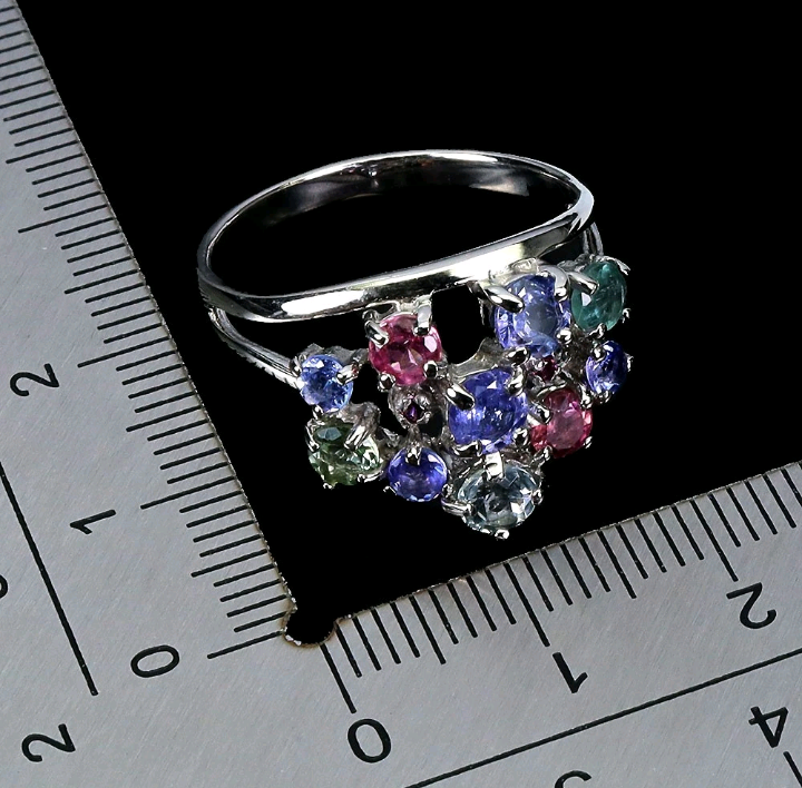 Silver ring with multicolored gemstones on a ruler for size reference