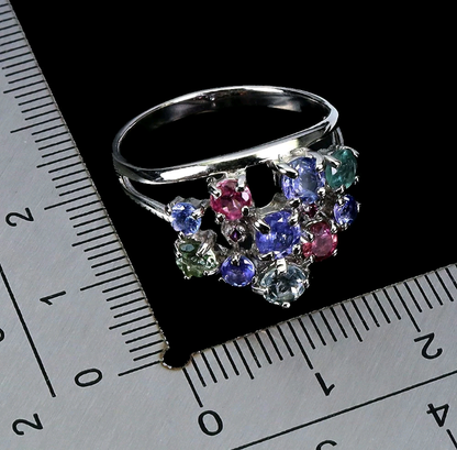 Silver ring with multicolored gemstones on a ruler for size reference