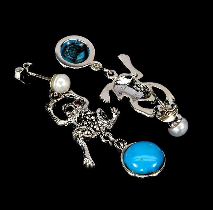 Silver earrings with blue and clear gemstones on a black background