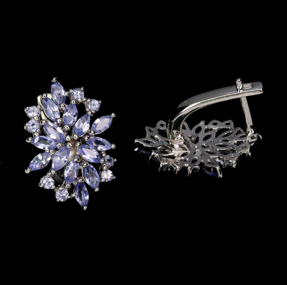 Pair of silver earrings with purple gemstones on a black background