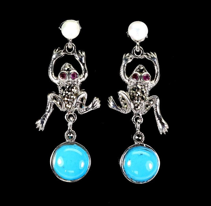 Frog-shaped earrings with turquoise stones on a black background
