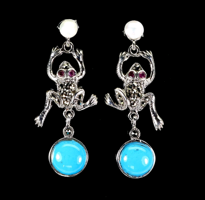 Frog-shaped earrings with turquoise stones on a black background