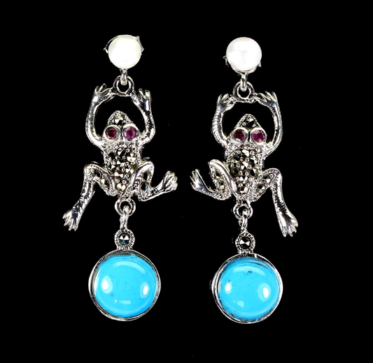 Frog-shaped earrings with turquoise stones on a black background