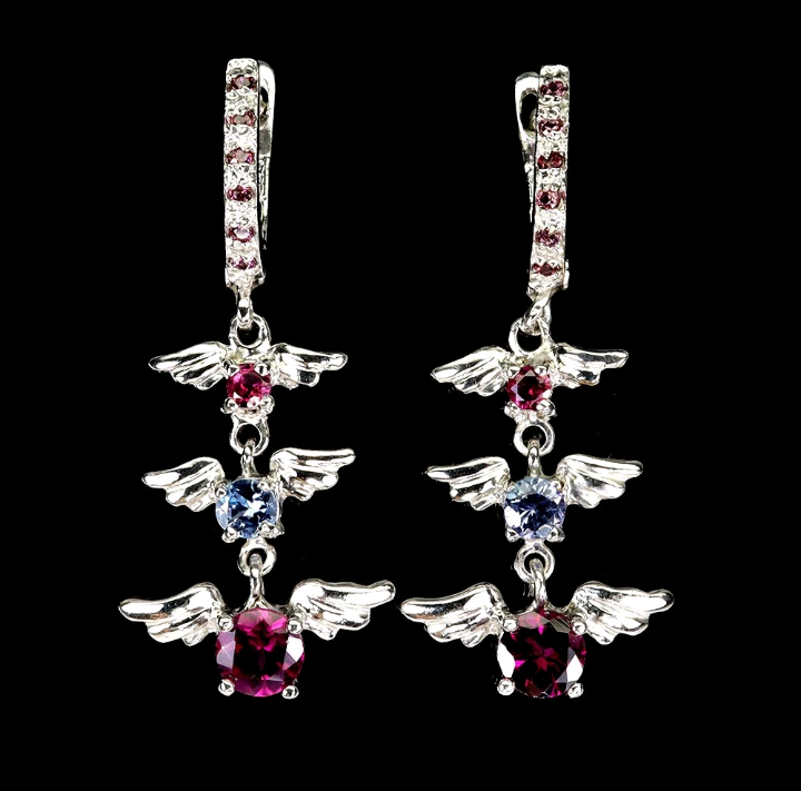 Pair of angel wing earrings with gemstones on a black background