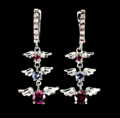 Pair of angel wing earrings with gemstones on a black background