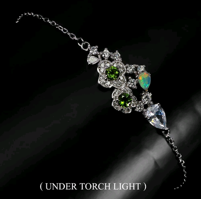 Delicate silver bracelet with green and opal stones on a dark background